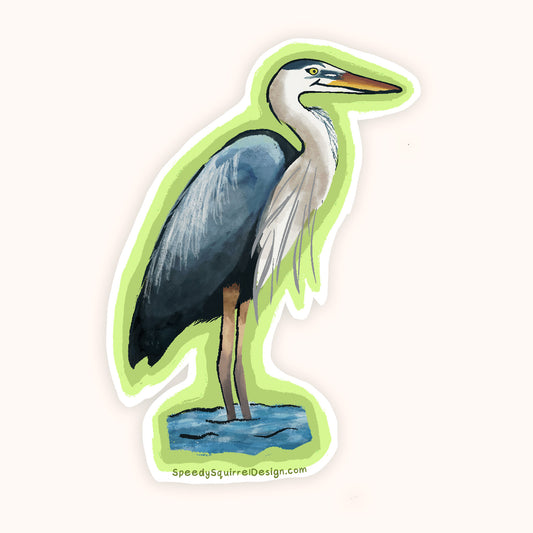 A die-cut sticker featuring a painted blue-gray heron standing in shallow blue water, with a white border and a bright green shadow effect behind it, shown on a plain light background. The website SpeedysSquirrelDesign.
