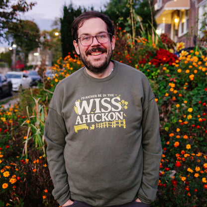 Man wearing a green sweatshirt with 'WISS Ahickon' text standing in front of flowers