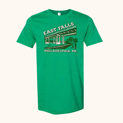 A green short-sleeve crewneck t-shirt featuring a vintage-style graphic of East Falls Twin Bridges with 'EAST FALLS' and 'PHILADELPHIA, PA' printed in white and dark green.