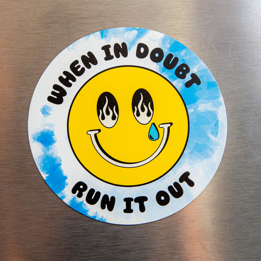 Circular sticker with smiley face and text 'When in doubt, run it out' on a metallic surface