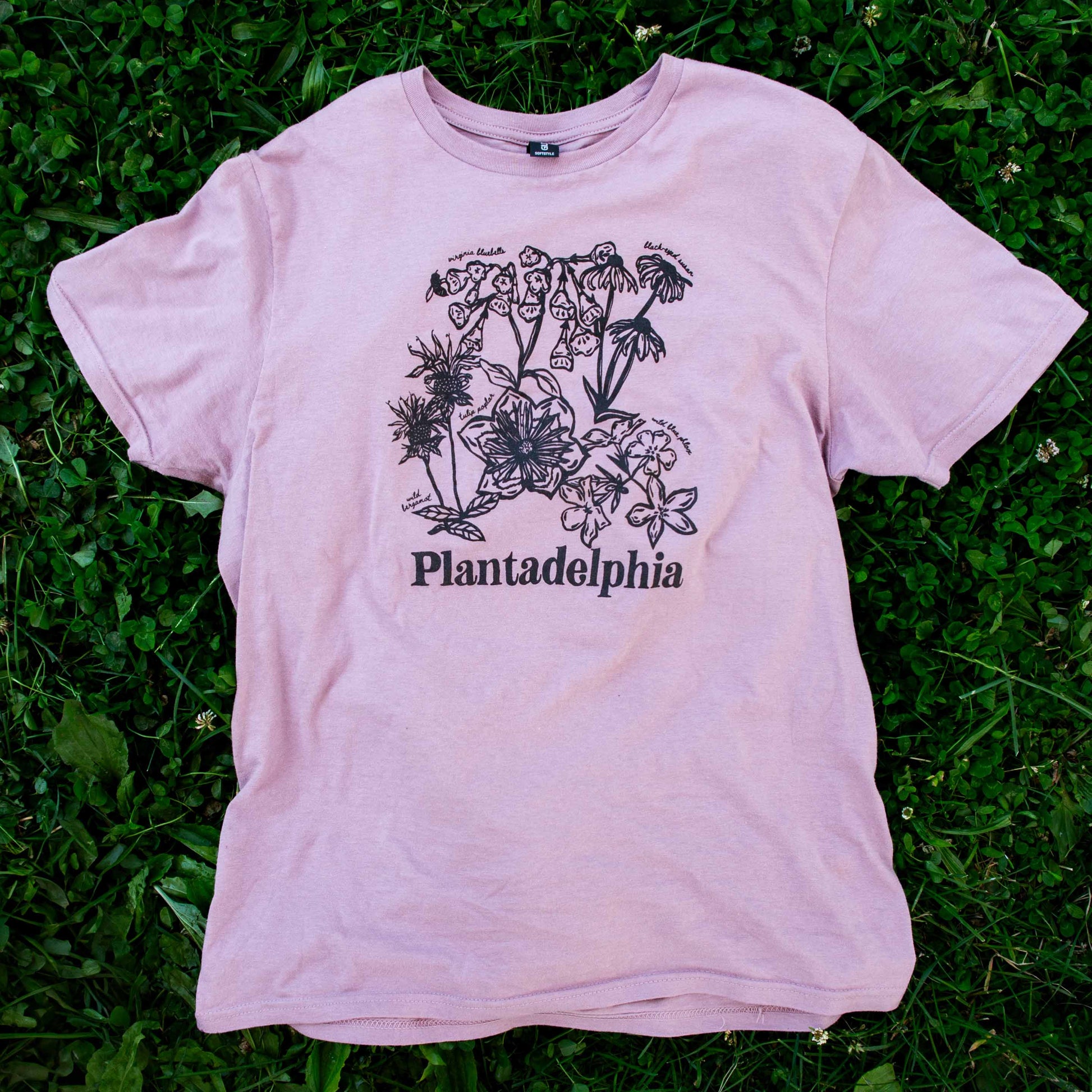 Lilac t-shirt with floral design and 'Plantadelphia' text on a grassy background