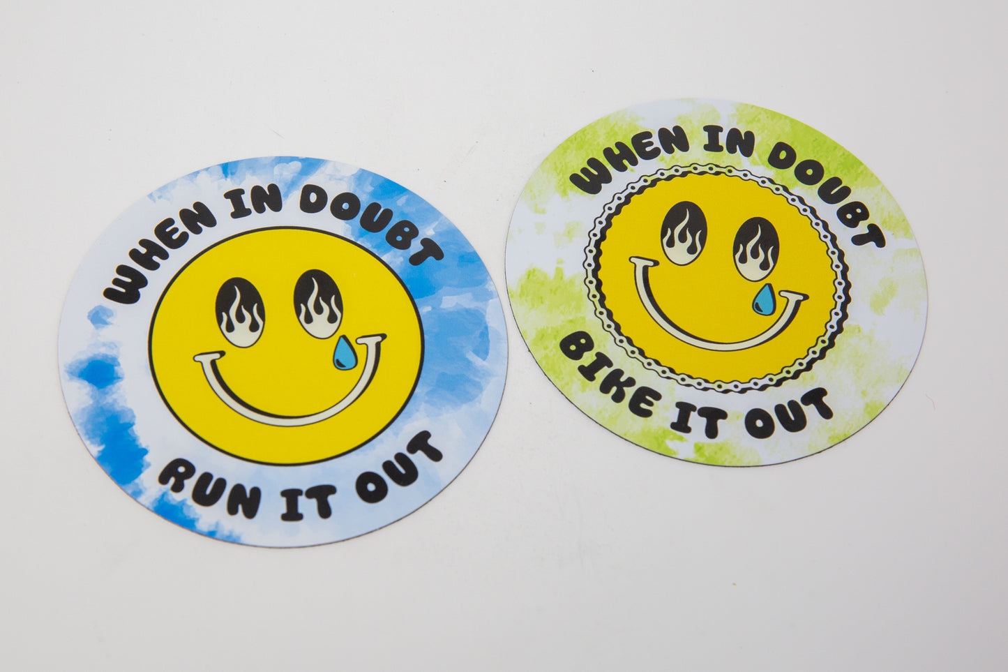 Two round stickers with smiley faces and text on a white background