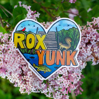 Heart-shaped sticker with 'ROX YUNK' text on a background of pink flowers