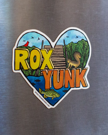 Heart-shaped sticker with 'ROX YUNK' text on a metallic surface