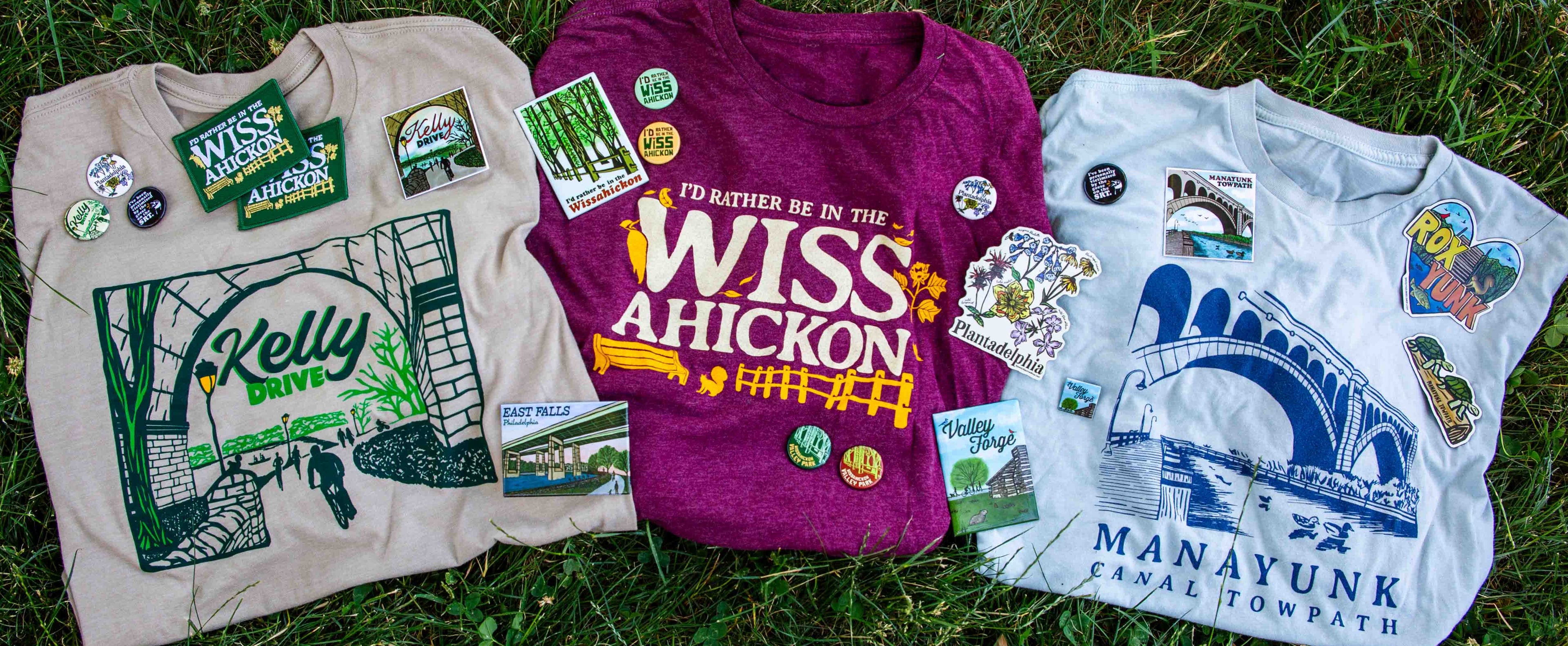T-shirts, magnets, pins, and patches of Philadlephia park illustrations laid on the grass