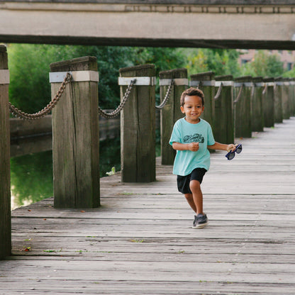 Child running on a wooden dock with a bridge in the background