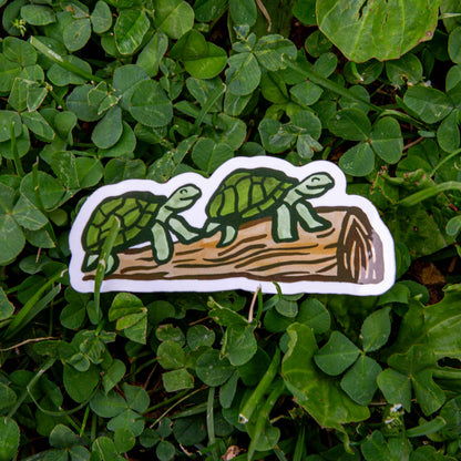 Two turtles smiling on a log sticker