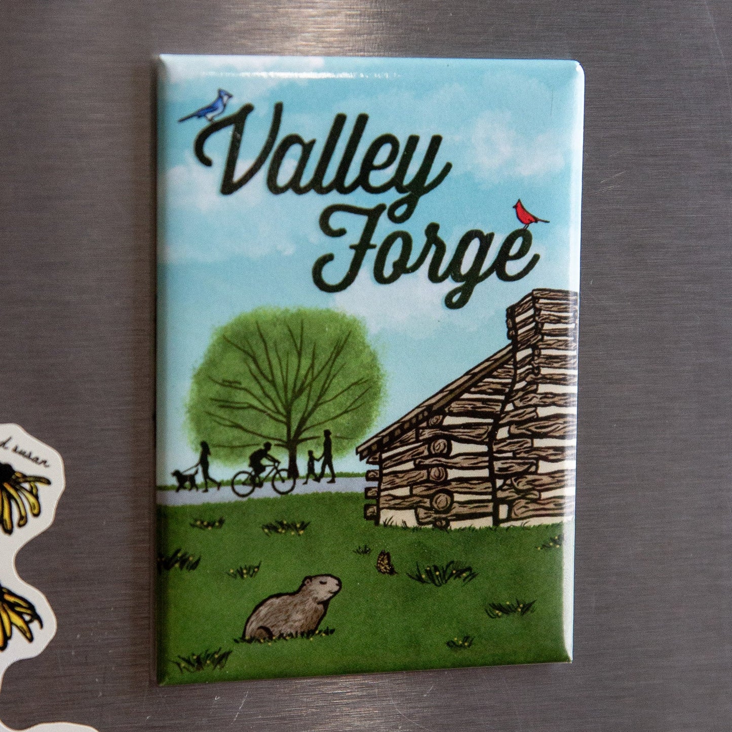 Fridge magnet with 'Valley Forge' design featuring a cabin and nature on a metallic surface.