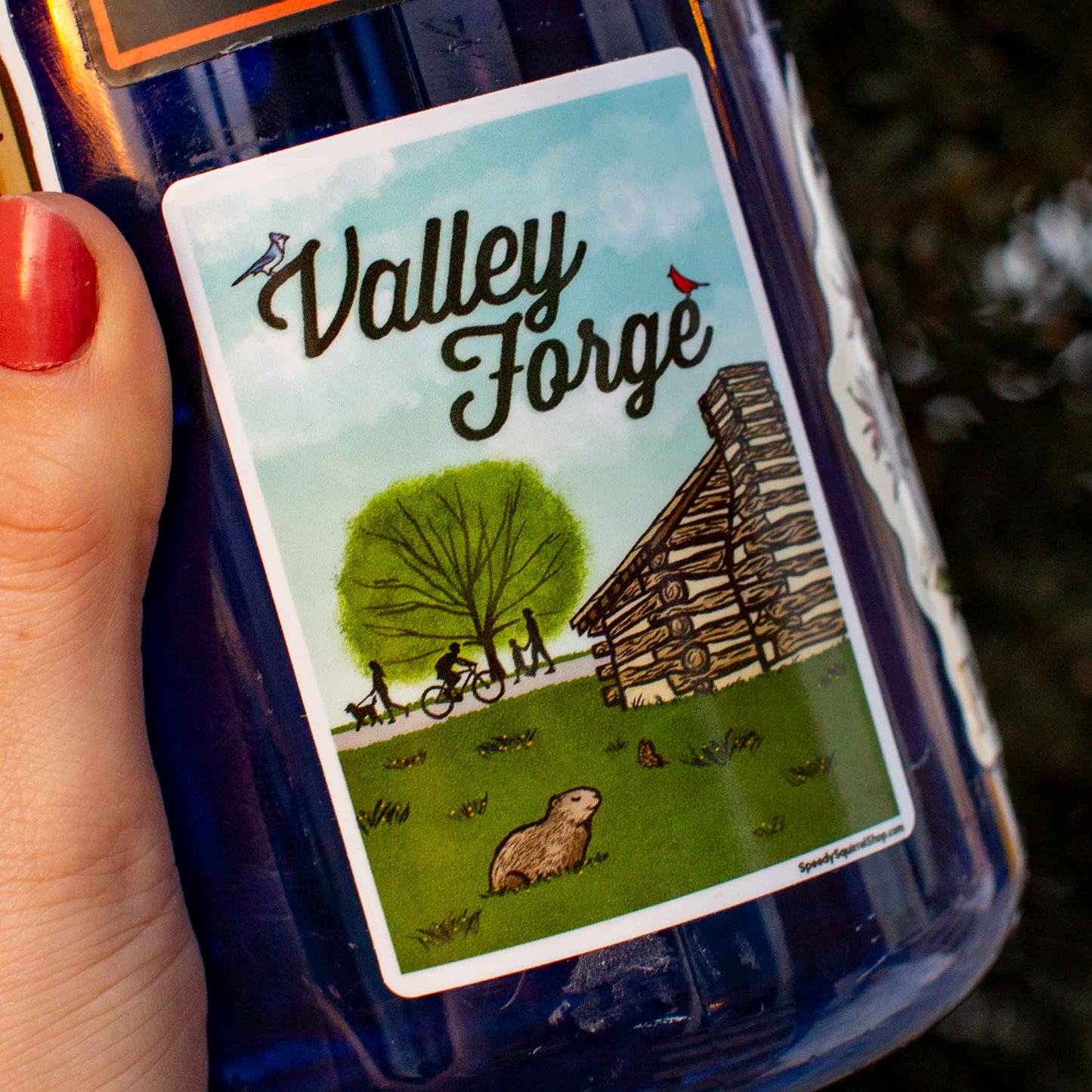 Bottle with a 'Valley Forge' sticker featuring illustrations of a cabin, tree, and people.
