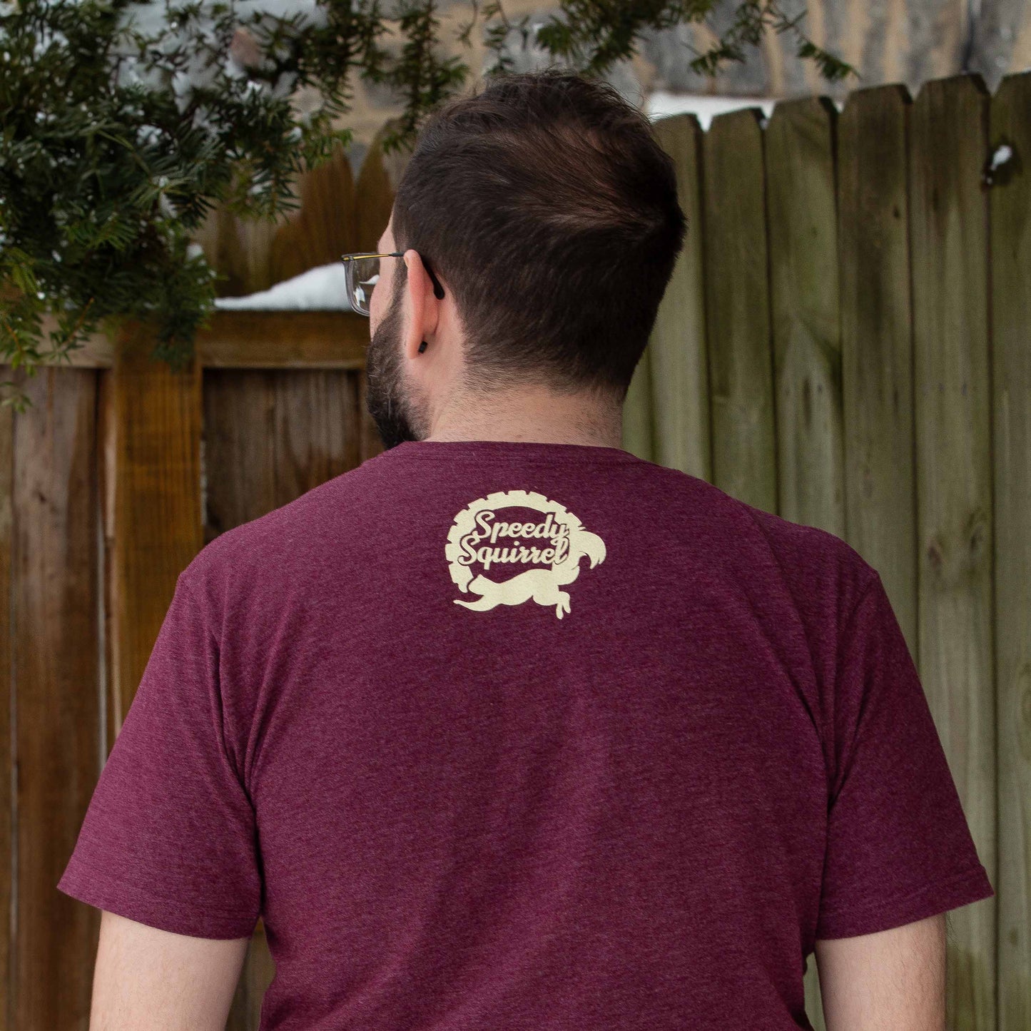 Man wearing a maroon t-shirt with the Speedy Squirrel logo on the nap of the neck